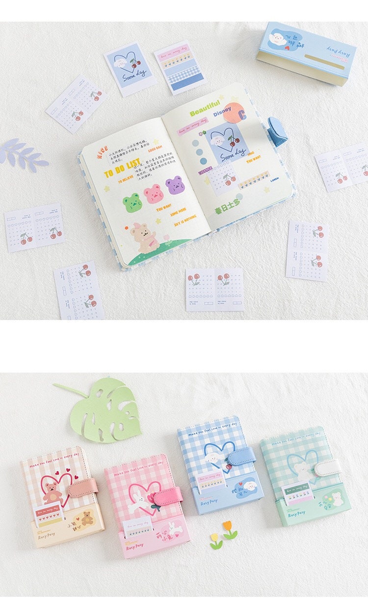 Magnetic Buckle Leather Grid Planner - Blue A6 Notebook with open pages showing colorful illustrations and to-do lists, surrounded by cute notecards. Various colors and designs of grid planners are displayed below, including pink, blue, and mint green. Ideal for kawaii stationery lovers.