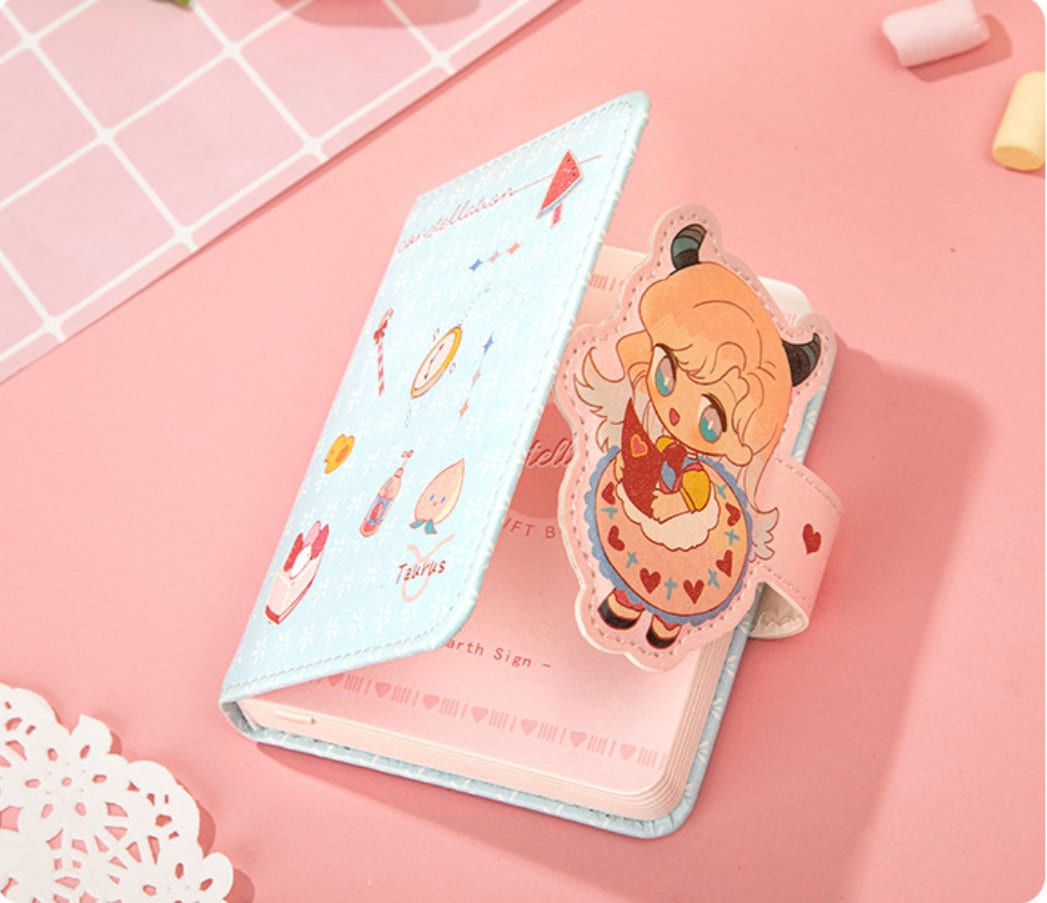 Zodiac Leather Journal with Magnetic Buckle Design featuring a cute Taurus character and pastel illustrations on a pink background.