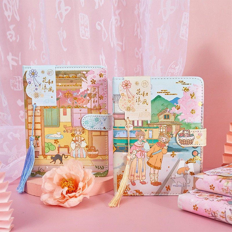 Cherry Blossom Planner - Soft Leather, Magnetic Buckle, kawaii stationery with pastel colors, featuring traditional Japanese artwork, decorated with tassels, and floral accents.