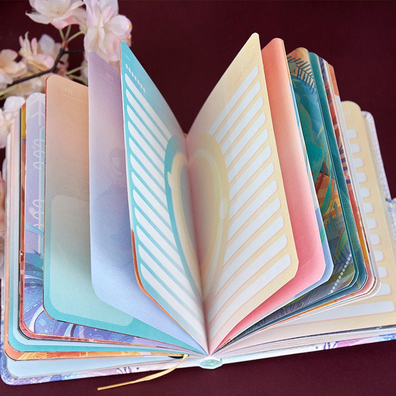 Leather journal with magnetic buckle opened to reveal colorful, aesthetic planner pages featuring pastel and artistic designs. Ideal for poems of life and cute stationery lovers.