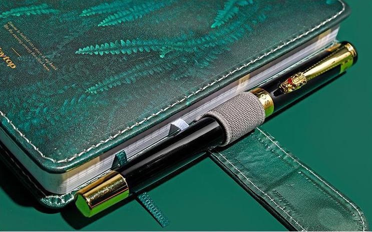 Tropical Leaf Journal with magnetic buckle and green leather cover, featuring a pen holder with a gold and black pen attached