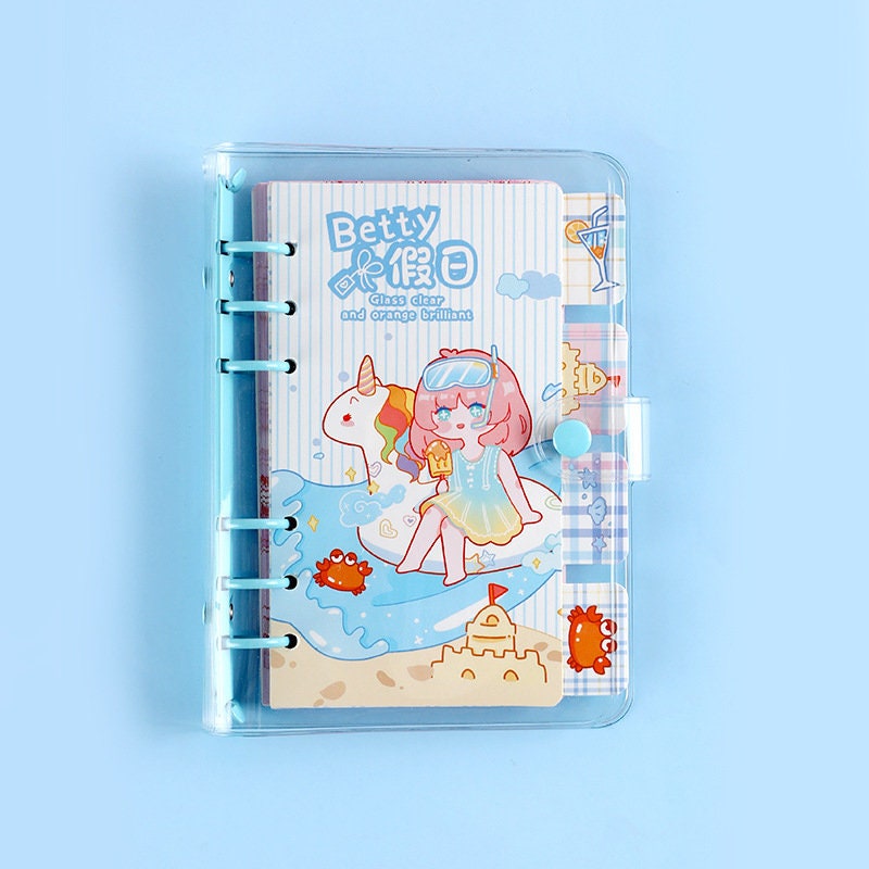 Betty's Vacation B6 Loose Leaf Planner featuring a cute girl with pink hair, wearing sunglasses, holding an ice cream cone and sitting on a unicorn float at the beach with whimsical illustrations of crabs, a sandcastle, and cocktails.