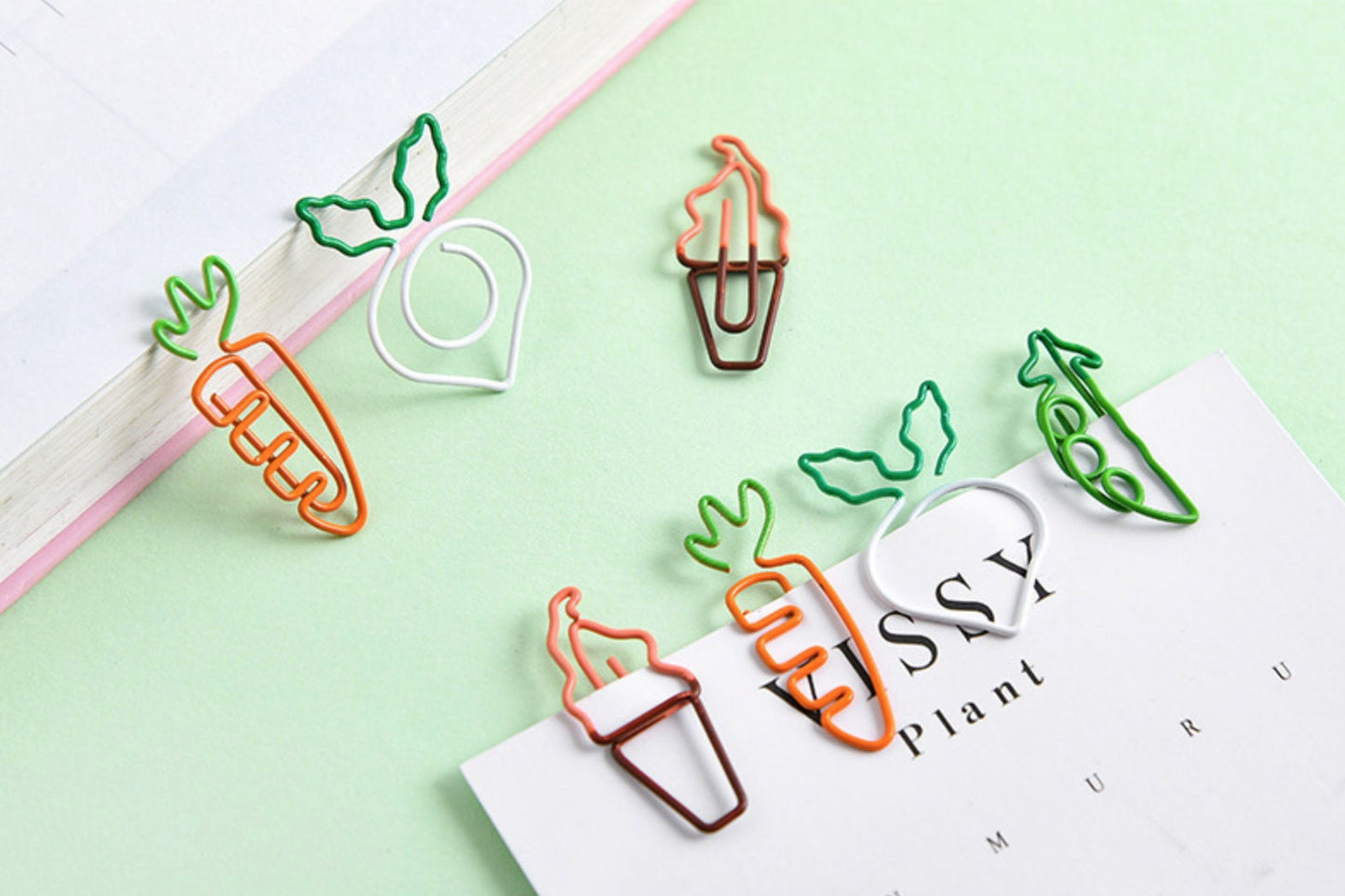 Creative Vegetable Clips in different shapes - carrot, radish, pea pod, and ice cream cone. Cute stationery and office supplies for organizing papers. Kawaii style wire paper clips on pastel background.