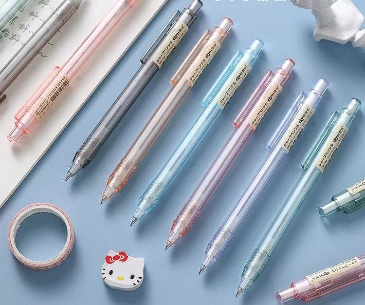 0.5mm transparent mechanical pencils in various pastel colors arranged on a light blue surface with accompanying kawaii stationery items.