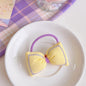 Kawaii Bowknot Hair Tie and Bracelet Combo in yellow with purple accents displayed on white plate with pastel plaid background.