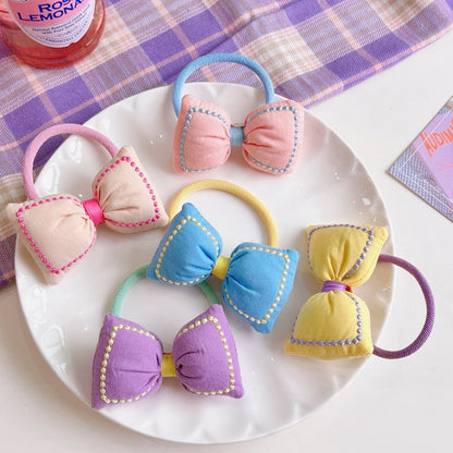 Kawaii Bowknot Hair Tie and Bracelet Combo in pastel colors, featuring cute bow designs with detailed stitching, displayed on a white plate with a pastel plaid background.