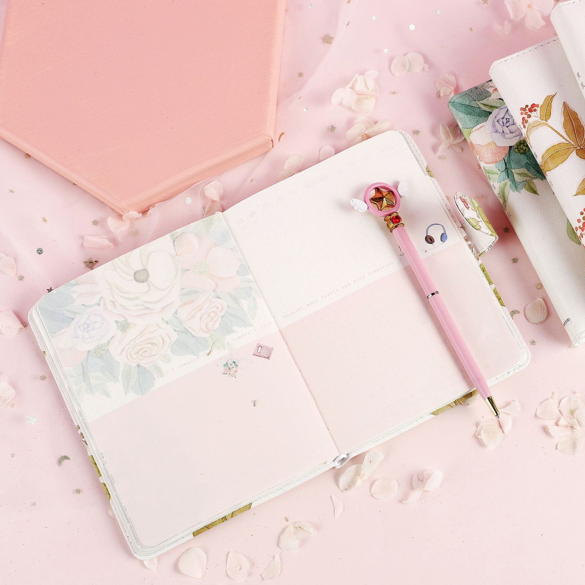 Like Wind Fog Cloud Leather Journal with Magnetic Buckle on pastel pink background, featuring floral illustrations and a pink decorative pen.