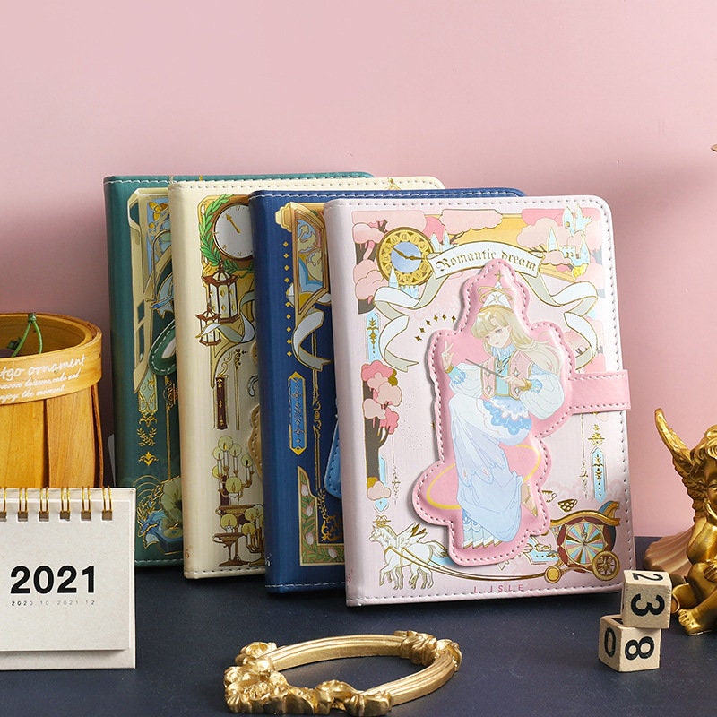 Romantic Dream Leather Journal - Magnetic Buckle A5 Notebook in kawaii style with pastel cover designs and intricate details, displayed in a set on a desk with various other items.