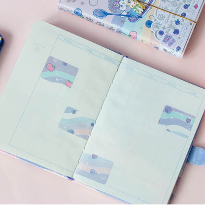 Rabbit Pudding Leather Journal with Magnetic Buckle open to a calendar page, displaying kawaii-style stickers and a whimsical design.