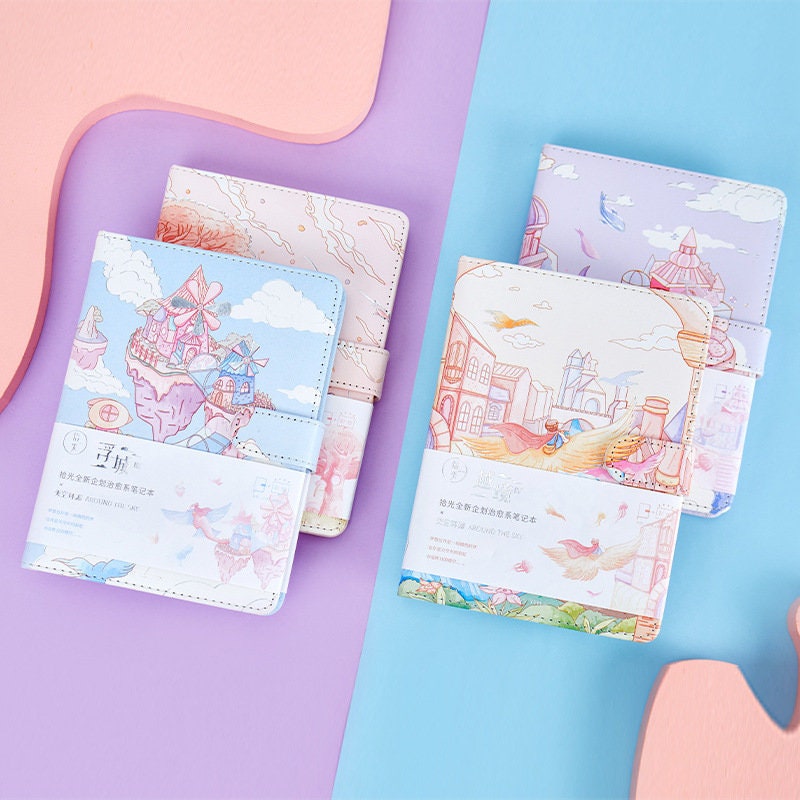 Magnetic Buckle Leather Journal with Around the Sky Design, featuring pastel colors and whimsical sky-themed illustrations on the cover.