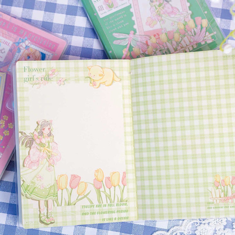 Magnetic Buckle Kawaii Flower Girl Notebook open on a checkered background showing pastel green and white pages with a cute illustration of a flower girl and tulips.