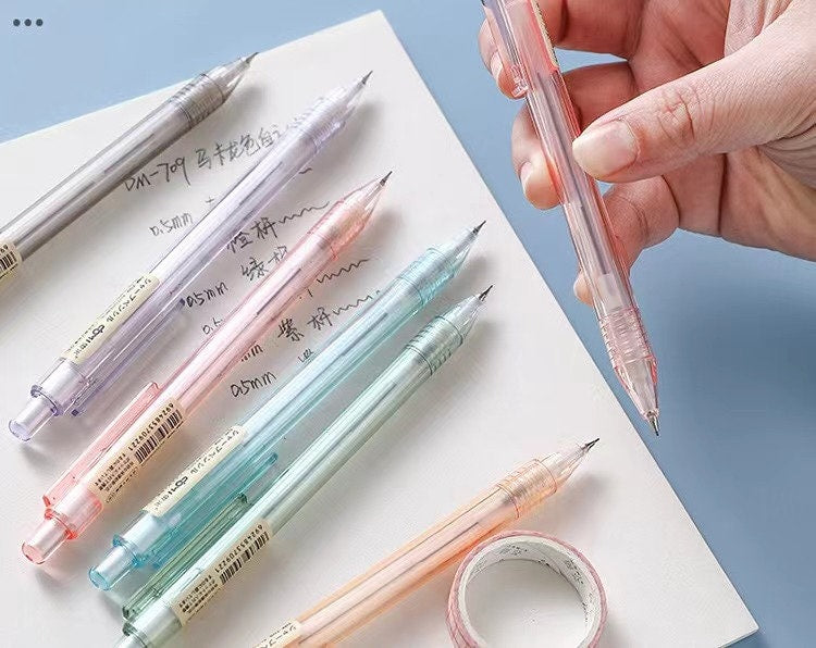 0.5mm transparent mechanical pencil in assorted pastel colors, minimalist office stationery, kawaii style, perfect for writing and drawing, displayed on white paper.