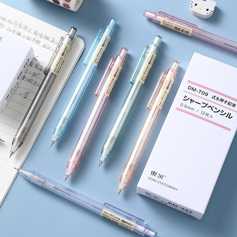 0.5mm transparent mechanical pencil, minimalist office stationery in assorted pastel colors, laid out on a blue desk with notebook and packaging nearby.