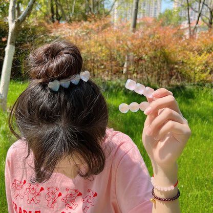 Girl wearing acrylic resin heart snap clips in her hair, holding additional clips, perfect for back to school, cute hair accessories for girls