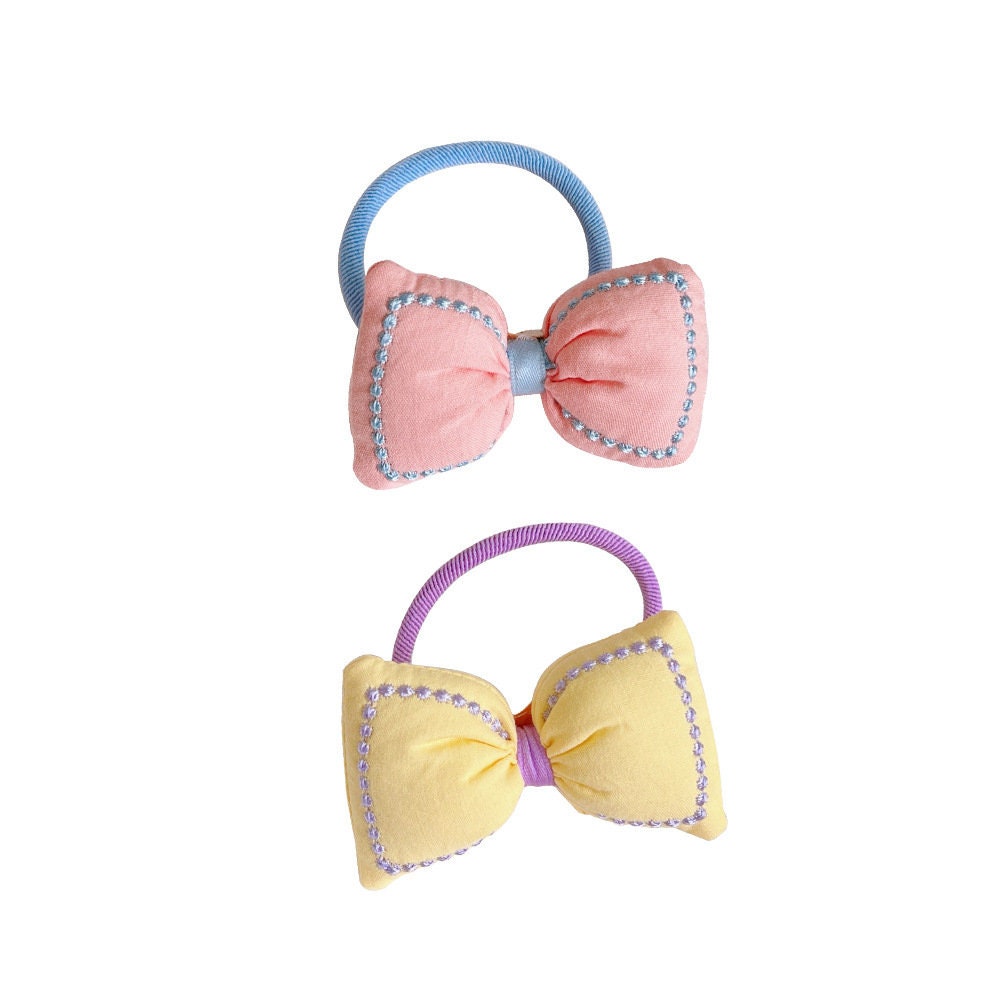 Kawaii Bowknot Hair Tie and Bracelet Combo in pastel pink and yellow with blue and purple accents, decorated with sparkling beads.