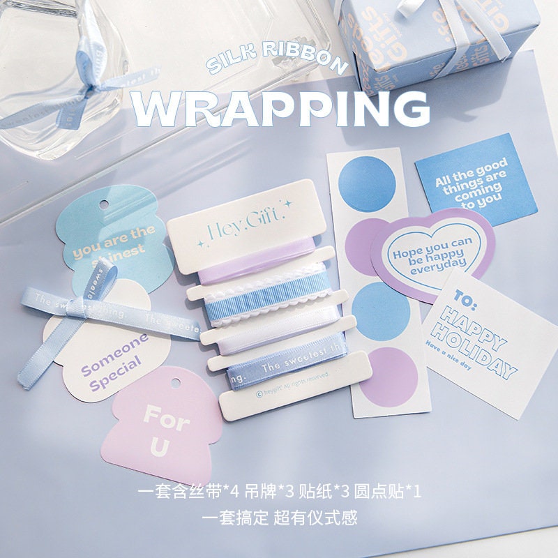 Gift Wrapping Ribbon Set with Stickers and Cards, featuring pastel blue and lavender silk ribbons, decorative tags, circular stickers, and holiday greeting cards. Perfect for cute and stylish gift wrapping.