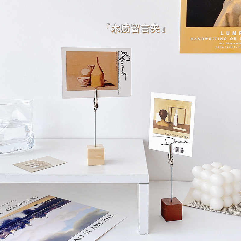 Creative Block Photo Holder with Clip displaying postcards on a minimalist white desk, featuring wooden blocks with metal clips, perfect for organizing and showcasing in kawaii style.