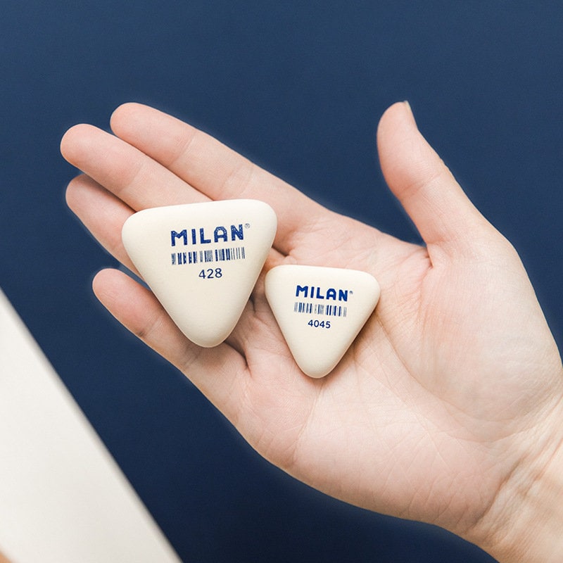 Hand holding two Milan erasers in different sizes against a dark blue background, showcasing the cute and chic design.