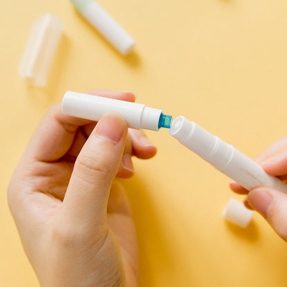 Hands holding a kawaii glue stick for scrapbooking and journaling with a yellow background.