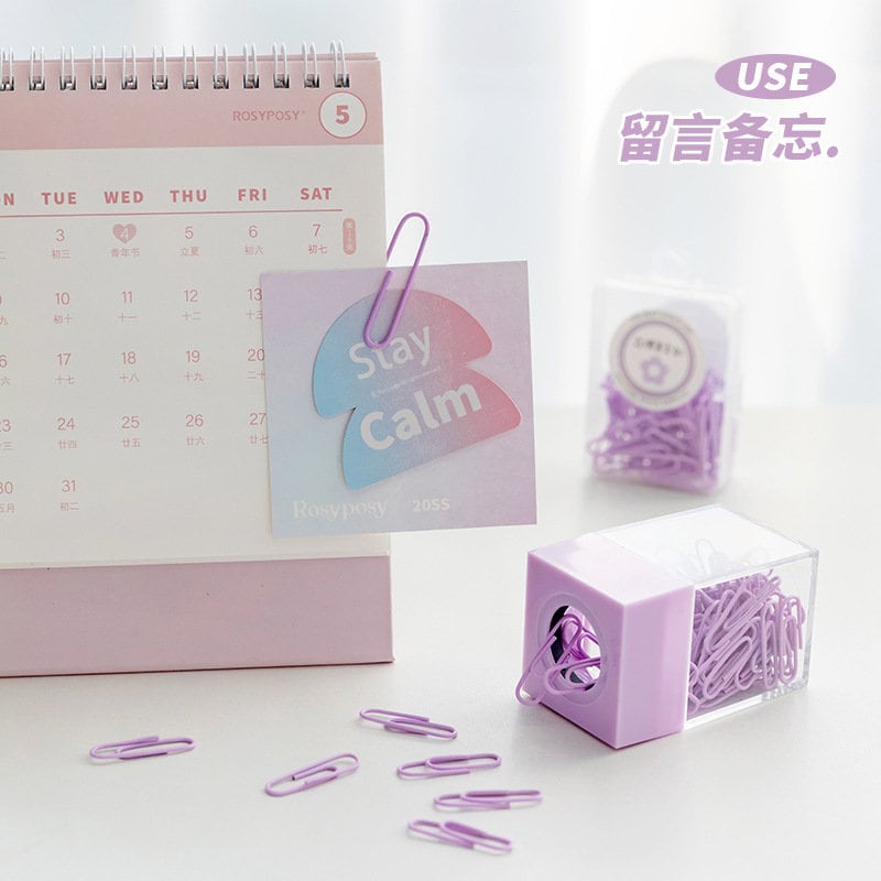 Pastel Office Paper Clips for Journals, Books & More in purple color, displayed with a pink desk calendar and note card.