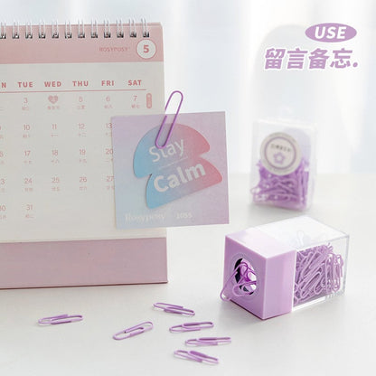 Pastel Office Paper Clips for Journals, Books & More in purple color, displayed with a pink desk calendar and note card.