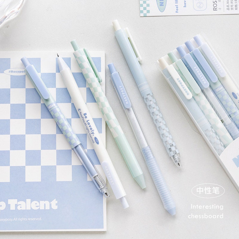 Pastel aesthetic gel pens - 5 pack 0.5mm quick dry, featuring soft pastel shades and chessboard patterns, displayed on a blue and white notebook, perfect for kawaii stationery collections.