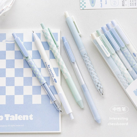 Pastel aesthetic gel pens - 5 pack 0.5mm quick dry, featuring soft pastel shades and chessboard patterns, displayed on a blue and white notebook, perfect for kawaii stationery collections.