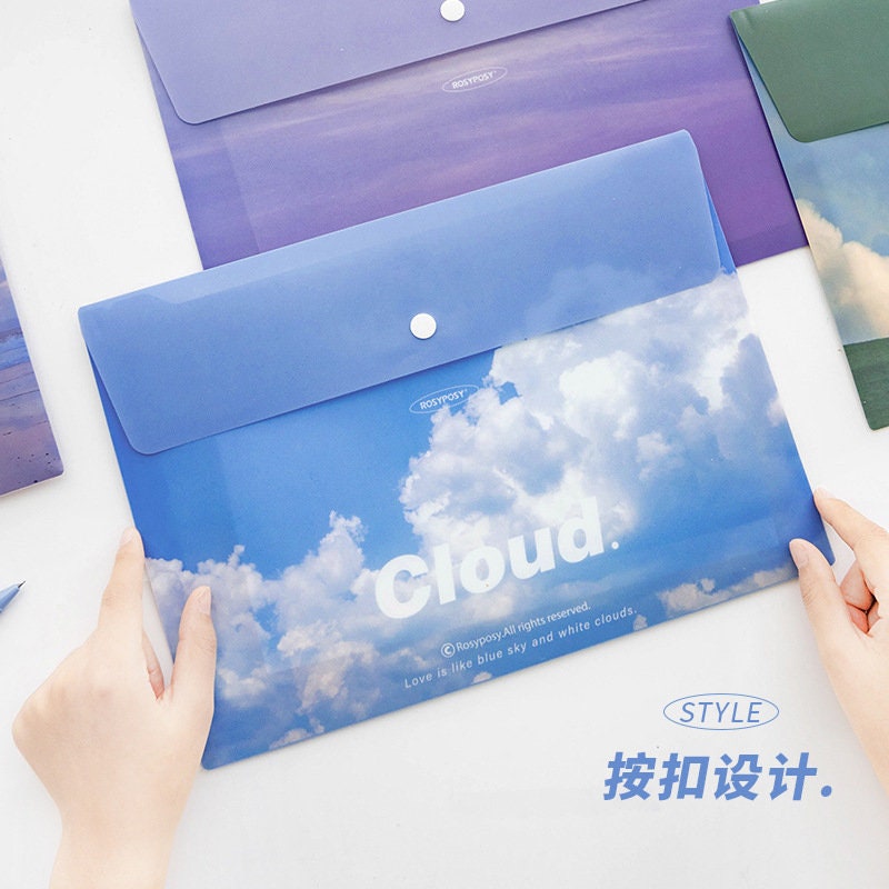 Portable A4 file folder with button closure featuring a blue sky and white clouds design, ideal for organizing documents and stationary in a kawaii style.