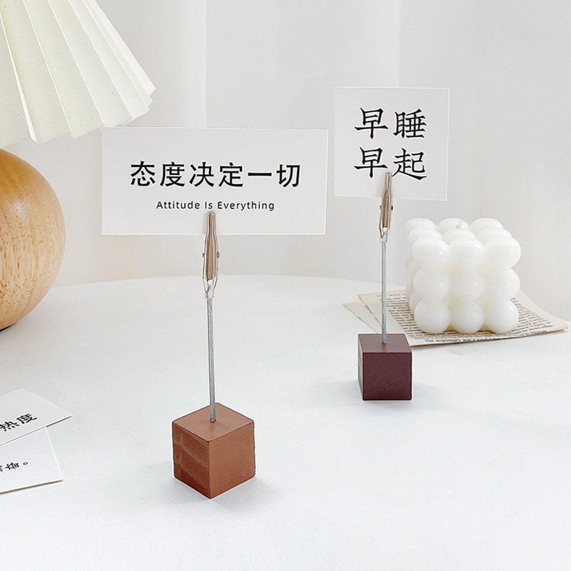 Creative Block Photo Holder with Clip featuring minimalistic design, displayed on a white surface with motivational cards and decorative items in the background.