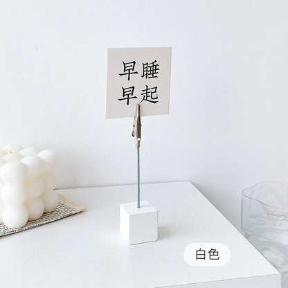 Creative Block Photo Holder with Clip in white on a table with decorative elements.