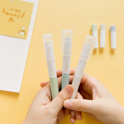 Kawaii Glue Stick for Scrapbooking and Journaling, held in hands with pastel-colored caps, perfect for arts and crafts on yellow background.