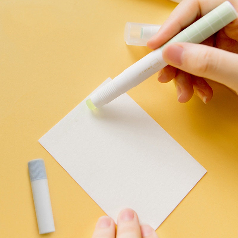 Kawaii glue stick being applied to a piece of white paper for scrapbooking and journaling on a yellow background.