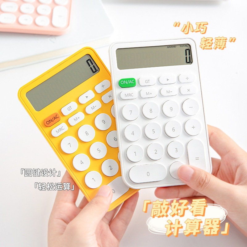 Yellow and white big button cute electronic calculators in kawaii style being held in hand.