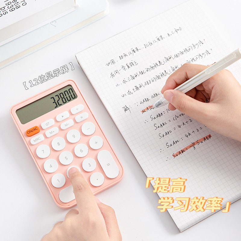 Big Button Cute Electronic Calculator in pink, being used to solve math problems on grid paper, featuring a 12-digit display.