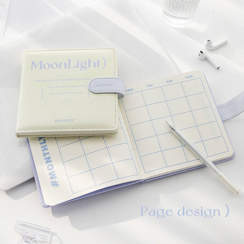 Moonlight Dreamer Colorful Journal - 84 Pages, soft pastel cover, open to show a weekly planner layout, white pen, kawaii stationery, stylish notebook for creativity and organization.